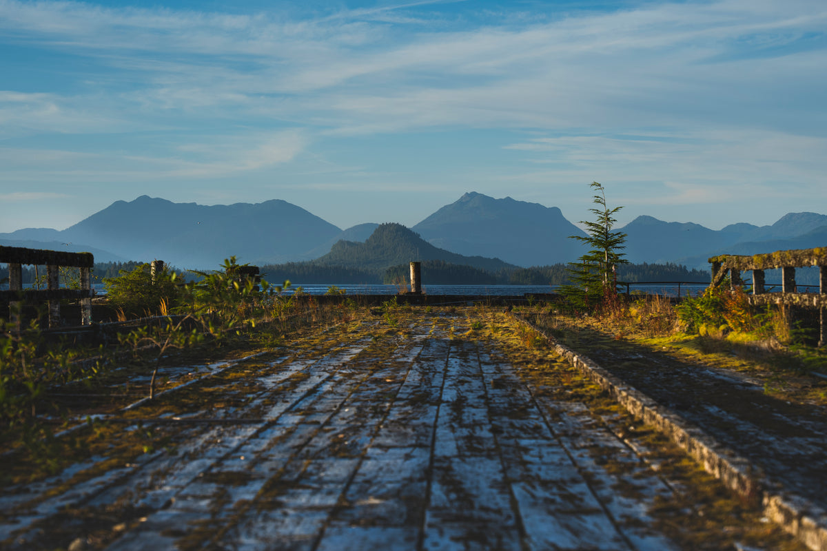 Weathered waterfront boards lead toward forested islands and mountains