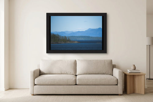 Illustrative room preview of Blue Mountain Passage in a black frame above a light sofa. Artwork scale is approximate.