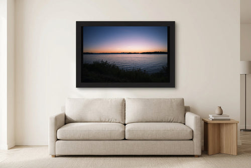 Illustrative room preview of Last Light on the Water in a black frame above a light sofa. Artwork scale is approximate.