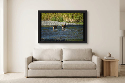 Illustrative room preview of Crossing Together in a black frame above a light sofa. Artwork scale is approximate.