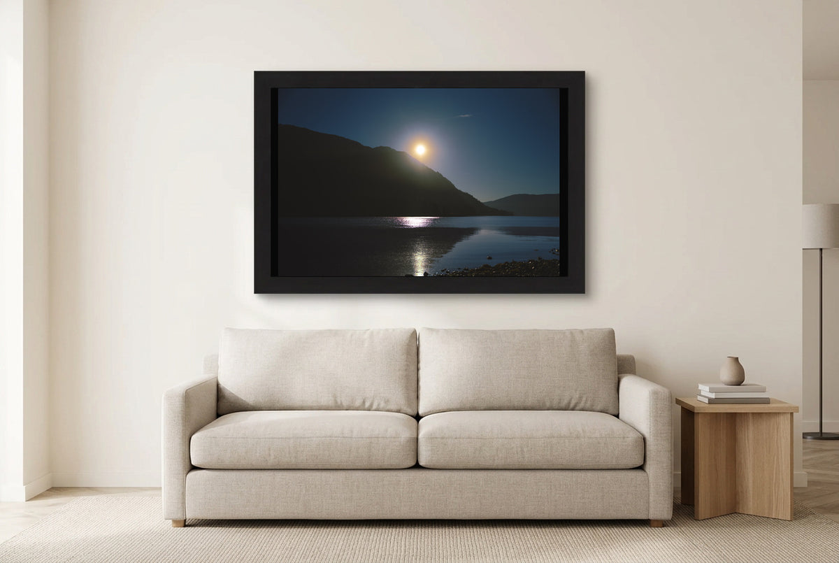 Illustrative room preview of Sun Above the Inlet in a black frame above a light sofa. Artwork scale is approximate.
